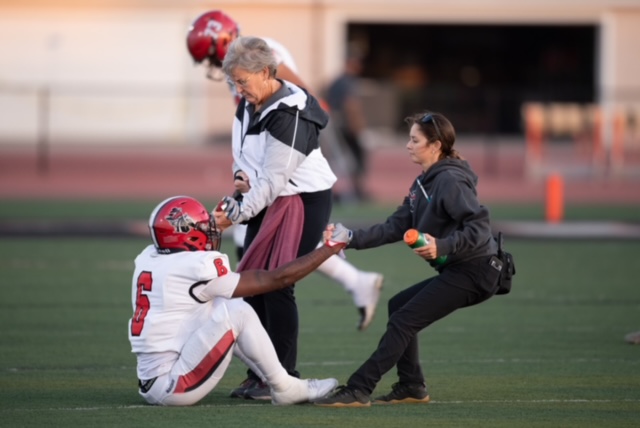 Athletic trainers helping a football player up